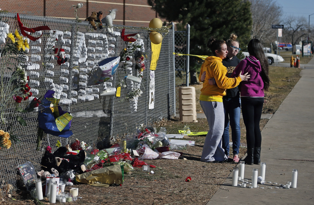 Arapahoe High School students hug after leaving items at a makeshift tribute site three days after a shooting attack at the school in Centennial, Colo., Monday, Dec. 16, 2013. They are, left to right, Hannah Eddy, Gavyn Bills, and Vania Arevalo. During the attack, the shooter shot a classmate in the head at close range with a shotgun, before killing himself.