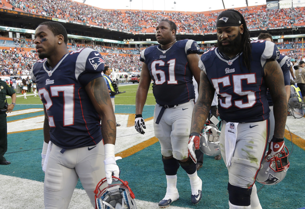 New England Patriots strong safety Tavon Wilson (27), tackle Marcus Cannon (61) and middle linebacker Brandon Spikes (55) walk off the field after they lost to the Miami Dolphins 24-20 in an NFL football game, Sunday, Dec. 15, 2013, in Miami Gardens, Fla. (AP Photo/Lynne Sladky)