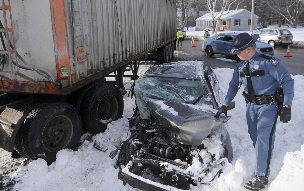 Serious crash: State Trooper Dane Wing walks around a car that was crushed beneath a tractor-trailer Wednesday afternoon on U.S. Route 202 in Manchester. The operator of the car was taken to the hospital.