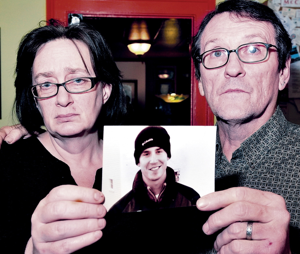 TRAGIC END: Lorna and Michael Smilek hold a 2006 photograph of Michael’s son, Justin Crowley- Smilek, who was shot and killed after he confronted Farmington police in 2011.