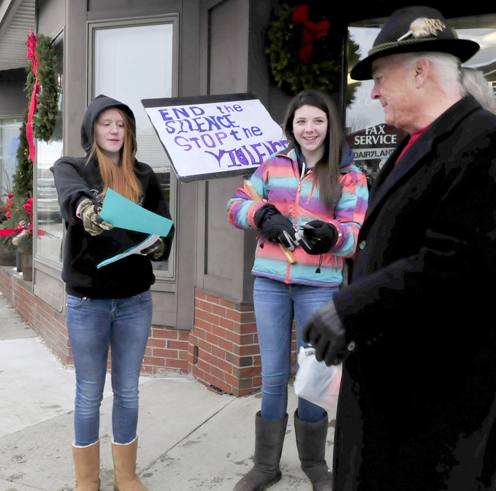 READ THIS: Mt. Blue High School students Tashia Berkey, left, and Cassie Ross distribute information about sexual violence during a silent demonstration on Main Street in Farmington on Thursday. Passerby Robert Underwood took some pamphlets.