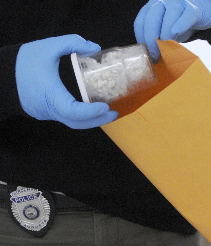 PUT AWAY: Augusta Police Department Officer Christopher Guay packages several doses of heroin seized Wednesday during the execution of a search warrant in Augusta.