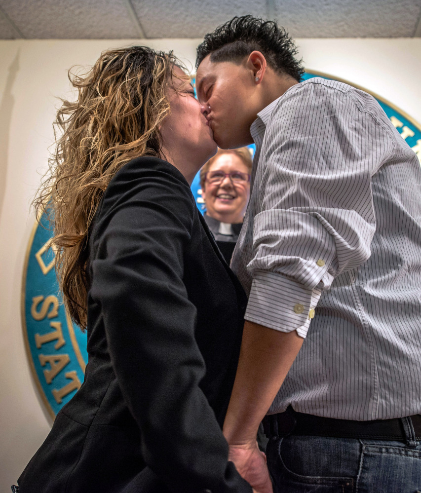 Desiree Padilla, left, and her partner Betty Garcia kiss after exchanging vows in a ceremony performed by the Rev. Judith Maynard, background, in Albuquerque, N.M., last summer. The New Mexico Supreme Court legalized same-sex marriage in the state Thursday, declaring in a ruling that it is unconstitutional to deny a marriage license to gay and lesbian couples.