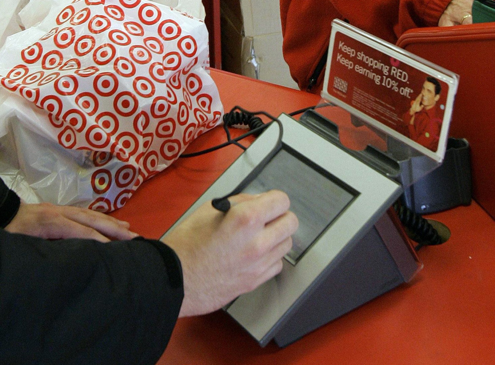 A customer signs after using his credit card. The data stolen recently included each user’s name, card number, expiration date and three-digit code.