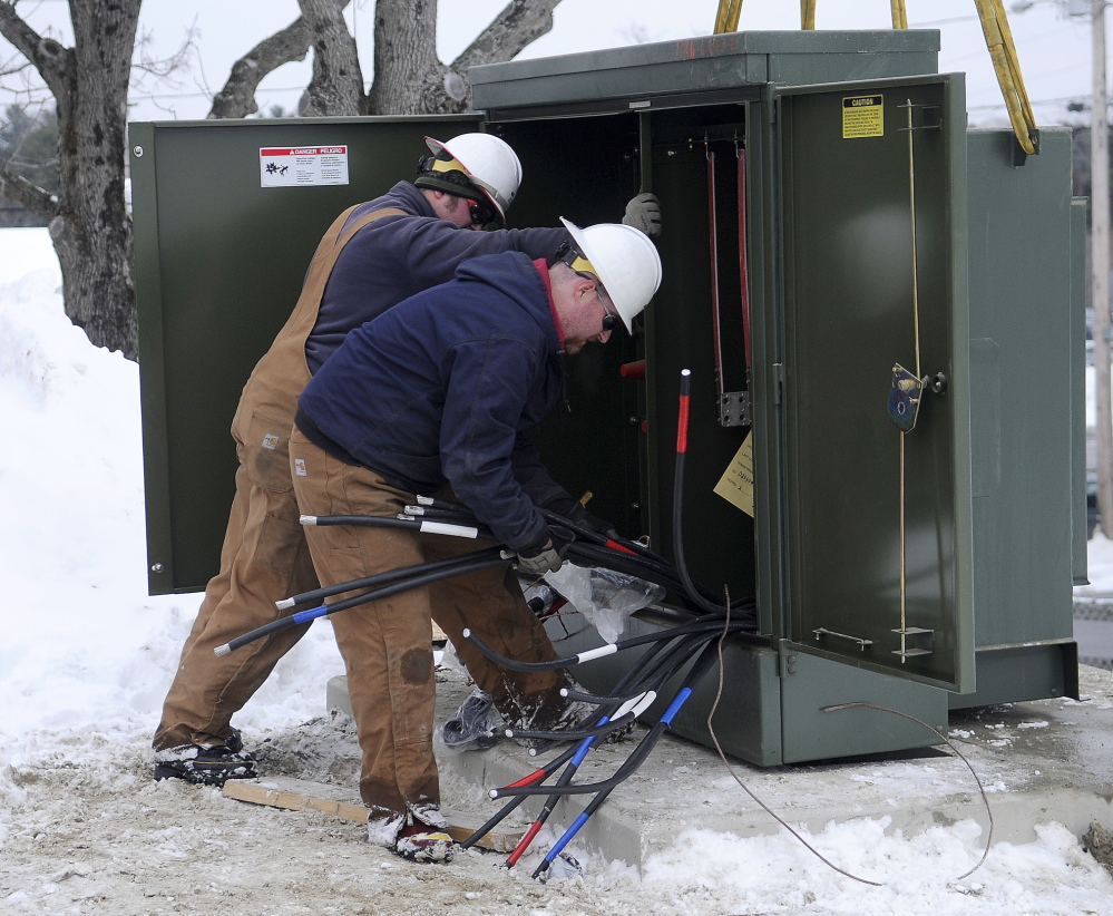 TURNED IT ON: Central Maine Power lineman Jason Hawes, right, and Garret Couturier install a power main Thursday in Augusta ahead of a potential ice storm forecast to arrive on Sunday.