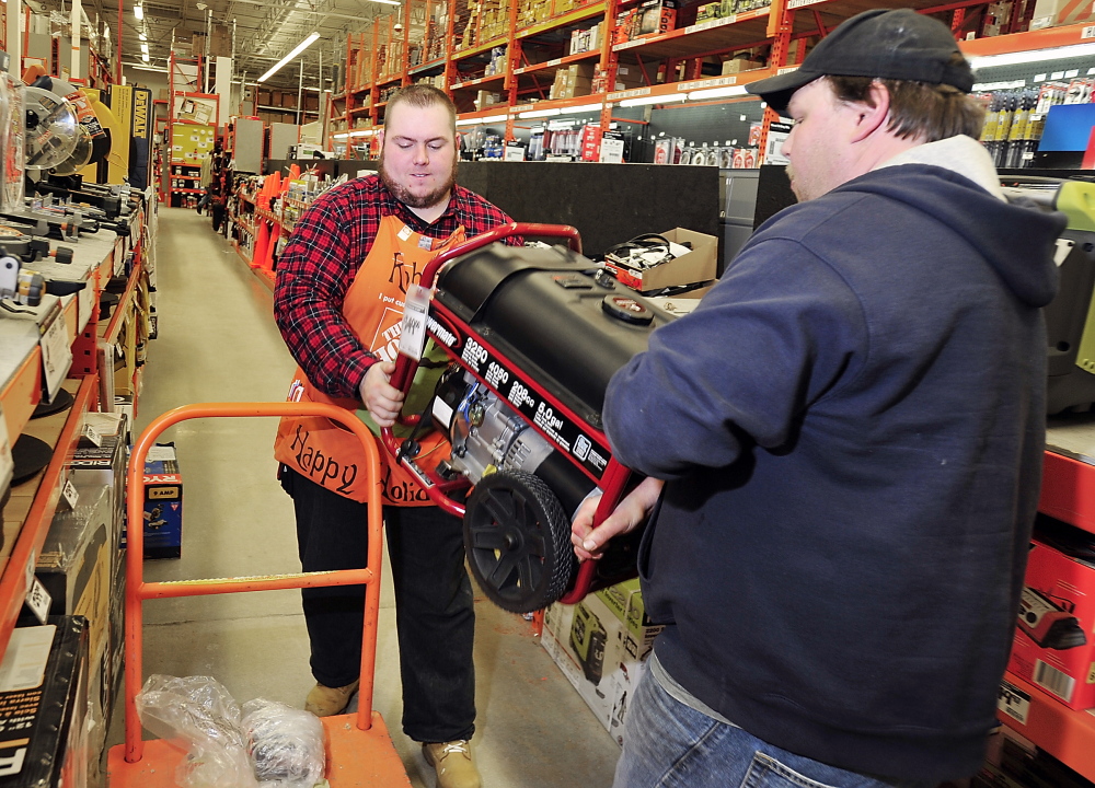 Josh Newell of Standish, right, helps Robert Muldowney, a hardware sales associate at the Home Depot in Portland, load a generator onto a cart for his mother in anticipation of possible electrical outages this weekend.