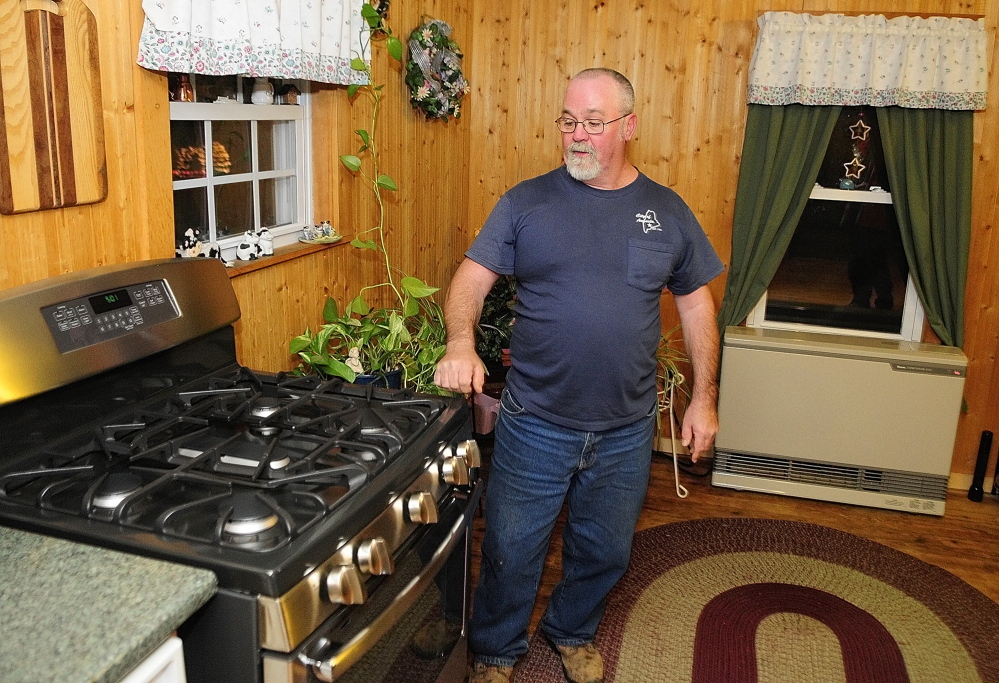 Switched: Dick Gagnon talks about the five burner kitchen stove, left, and direct vent heater, bottom right, that now run on natural gas in his Augusta home. Gagnon recently switched from propane to natural gas.
