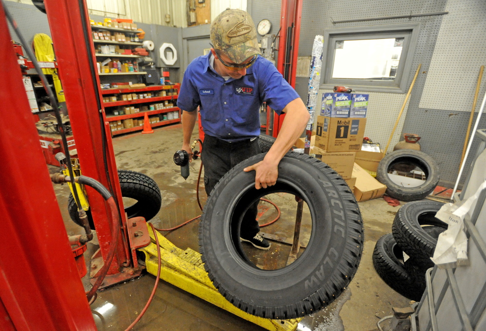NOW TIRE SEASON: Leland Bradford, 18, places a snow tire on a stand to install metal studs at VIP in Waterville on Saturday to stay ahead of the demand this winter.