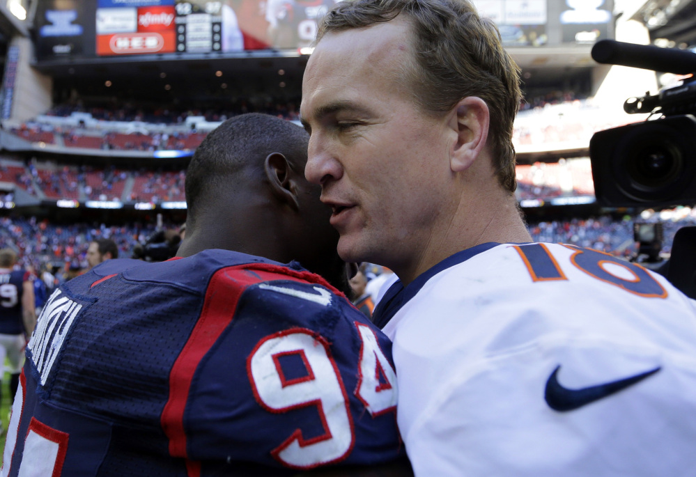 Denver Broncos’ Peyton Manning, right, hugs Houston Texans’ Antonio Smith (94) following an NFL football game, Sunday, Dec. 22, 2013, in Houston. Manning threw his 51st touchdown pass of the season to set a new NFL record.