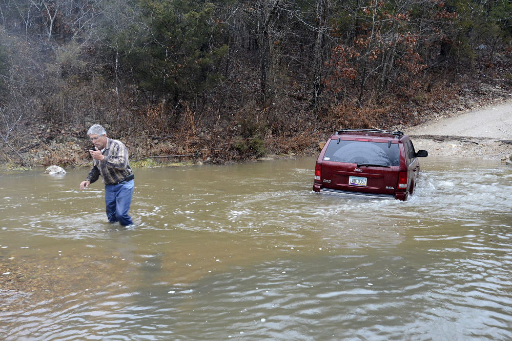 David Puffer calls for help after he stranded his vehicle in floodwaters on Saturday, Dec. 21, 2013 in Baxter County, Ark. The National Weather Service has issued a tornado watch in southeastern Arkansas and flood warnings and watches in much of the remainder of the state.