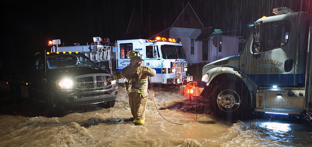 An Ellettsville fire fighter sets up a safety rope as they prepare to wade through moving flood water in Ellettsville, Ind., on Saturday, Dec. 21, 2013. National Weather Service meteorologist Mike Ryan says three to four inches of rain fell between Friday night and Saturday evening on the southwestern Indiana cities of Vincennes and Washington and further east in the Bedford and Bloomington areas. He says the heaviest bands of rain were expected to arrive Saturday night before tapering off early Sunday.