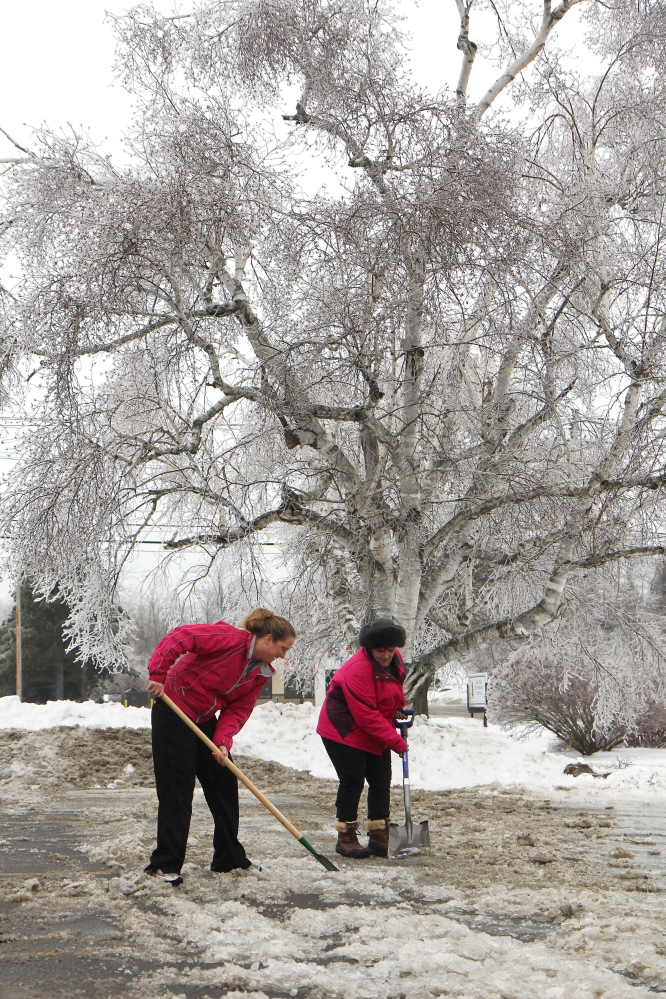 Photo by Jeff Pouland ICE WORK: Pine Tree Veterinary Hospital employees Shannon Clements, left, and Denise Nadeau work to clear their parking lot of thick ice at the clinic located off Western Avenue in Augusta on Monday. "I remember '98. I can live without that, " said Nadeau. Though this ice storm wasn't as bad as the one in '98, it still caused a lot of headaches for residents of central Maine.