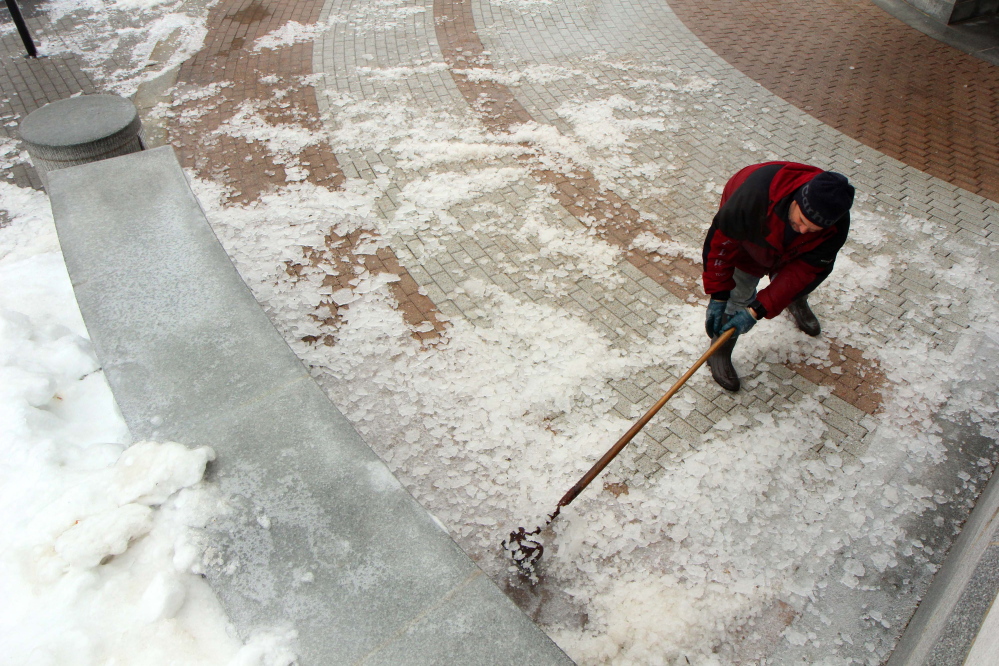 Photo by Jeff Pouland BREAKING IT UP: Clinton Coutts of the Bureau of General Services works to clear ice near an entrance to the State House in Augusta during Monday's storm.