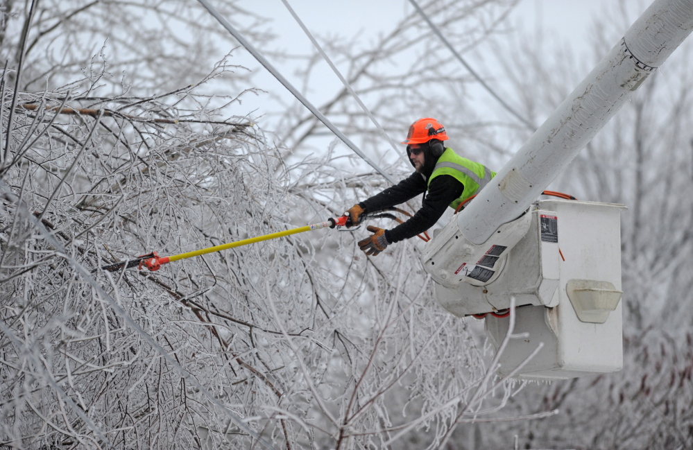 LINE CLEARING: Andrew Powers, an arborist with Asplundh Tree Experts, clears power lines from iced branches along Mayflower Heights Drive in Oakland on Monday.