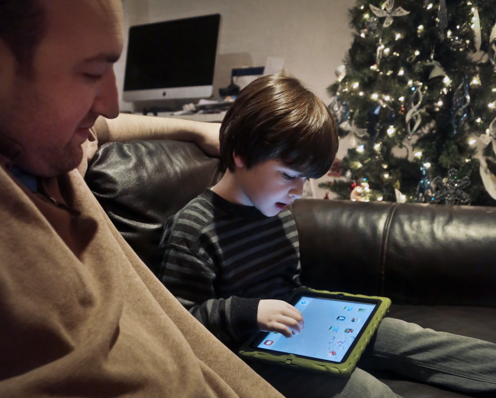 Adam Cohen looks as his son Marc, 5, uses a tablet at home in New York. Adam Cohen, a stay-at-home father of two, says apps have been a key part of Marc’s education since he was just a baby.