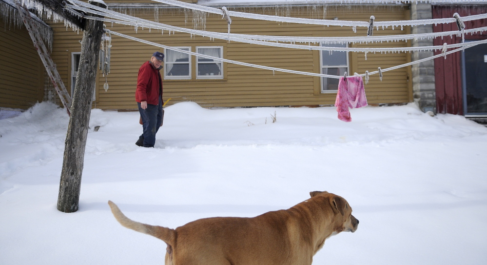 Staff photo by Andy Molloy SHELTER: Sonny Black walks past the frozen clothes line at his Litchfield farm after firing up the generator. Black had purchased a generator a few years ago to permit him to remain at the farm and tend to the herd of beef and dairy cows.