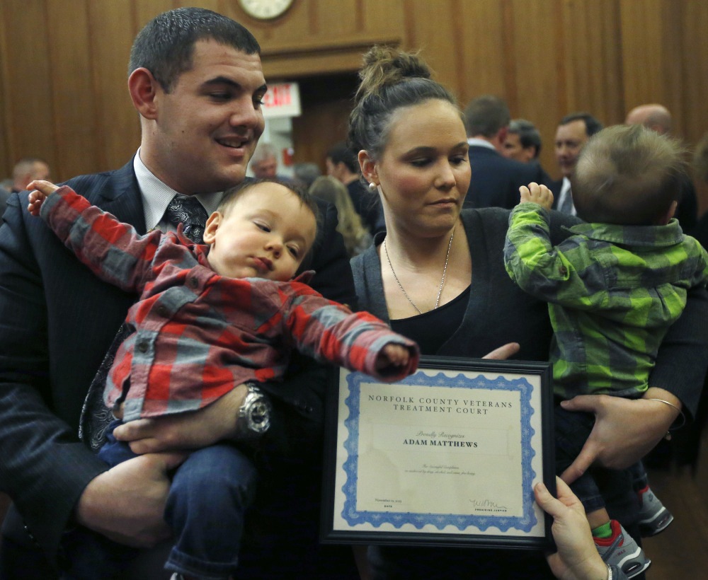 Adam Matthews, 23, of Bellingham, Mass., holds 10-month-old Jacob while his wife, Alexa, holds twin brother Jackson as they receive a certificate from the Norfolk County Veterans Treatment Court in Dedham, Mass.