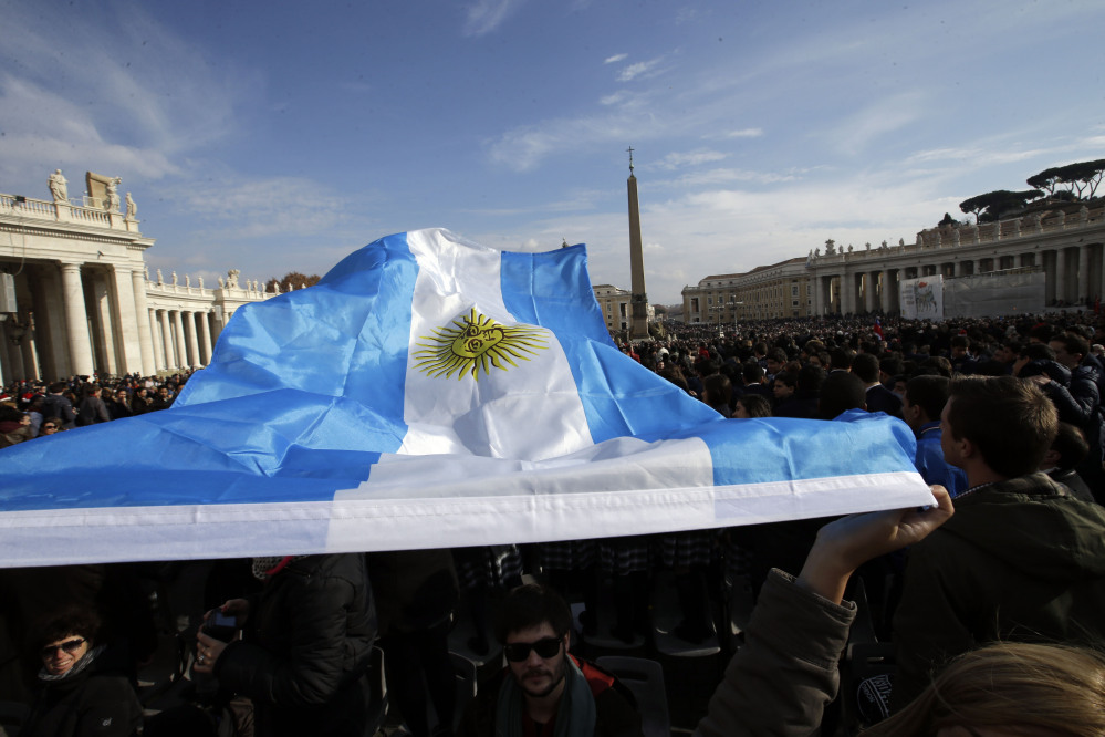 An Argentine flag is waved by faithful prior to Pope Francis “Urbi et Orbi” (to the City and to the World) message he delivered from the central balcony of St. Peter’s Basilica at the Vatican, Wednesday, Dec. 25, 2013. Pope Francis on Christmas day is wishing for a better world, with peace for the land of Jesus’ birth, for Syria and Africa as well as for the dignity of migrants and refugees fleeing misery and conflict. Francis spoke from the central balcony of St. Peter’s Basilica Wednesday to tens of thousands of tourists, pilgrims and Romans in the square below. He said he was joining in the song of Christmas angels with all those hoping “for a better world,” and with those who “care for others, humbly.”