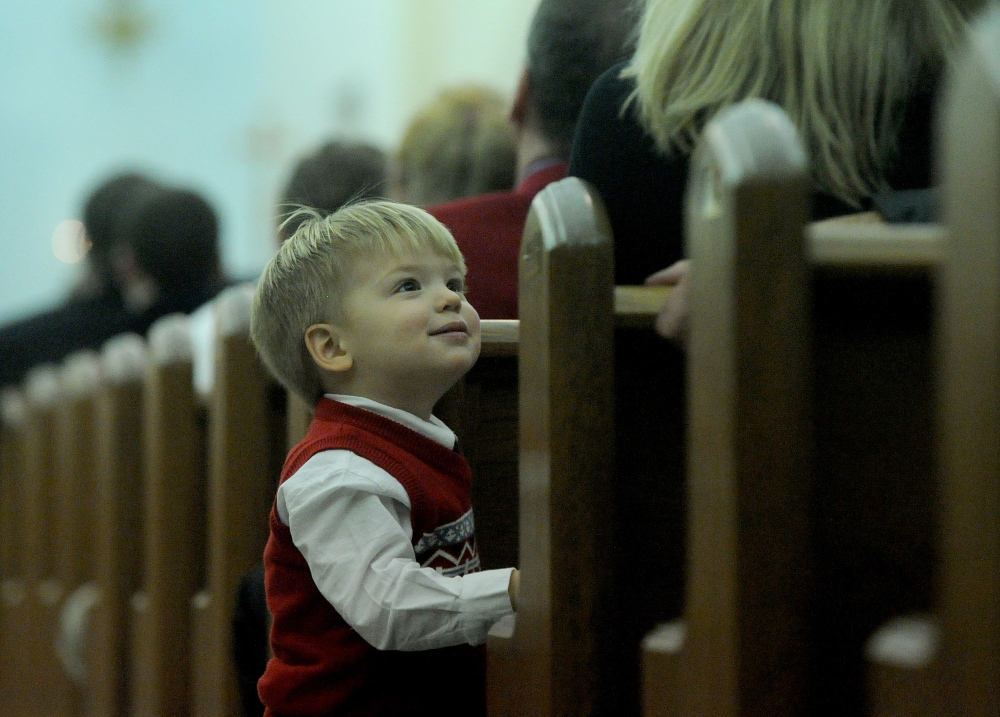 Staff photo by Michael G. Seamans CHRISTMAS IN WATERVILLE: Brody Jabar, 1, looks to his mother for some entertainment Heather during the Christmas Eve Liturgy at St. Joesph's Maronite church in Waterville on Tuesday, Dec. 24, 2013.