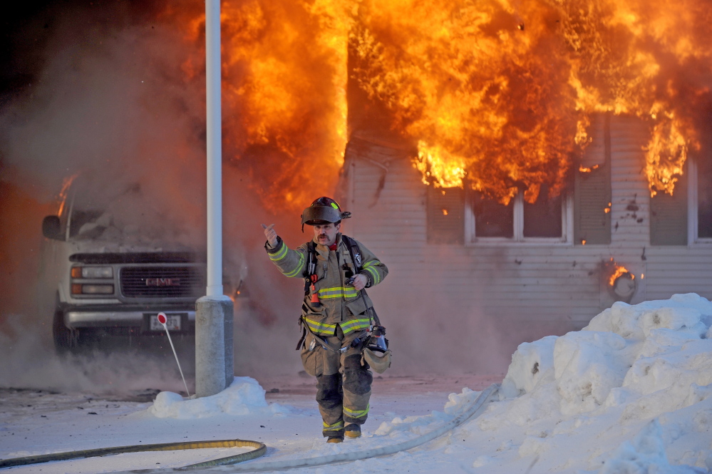 Staff photo by Michael G. Seamans CHRISTMAS FIRE: A Waterville firefighter gestures to other firefighters after arriving at an active fire at 160 Drummond Ave. in Waterville on Wednesday.