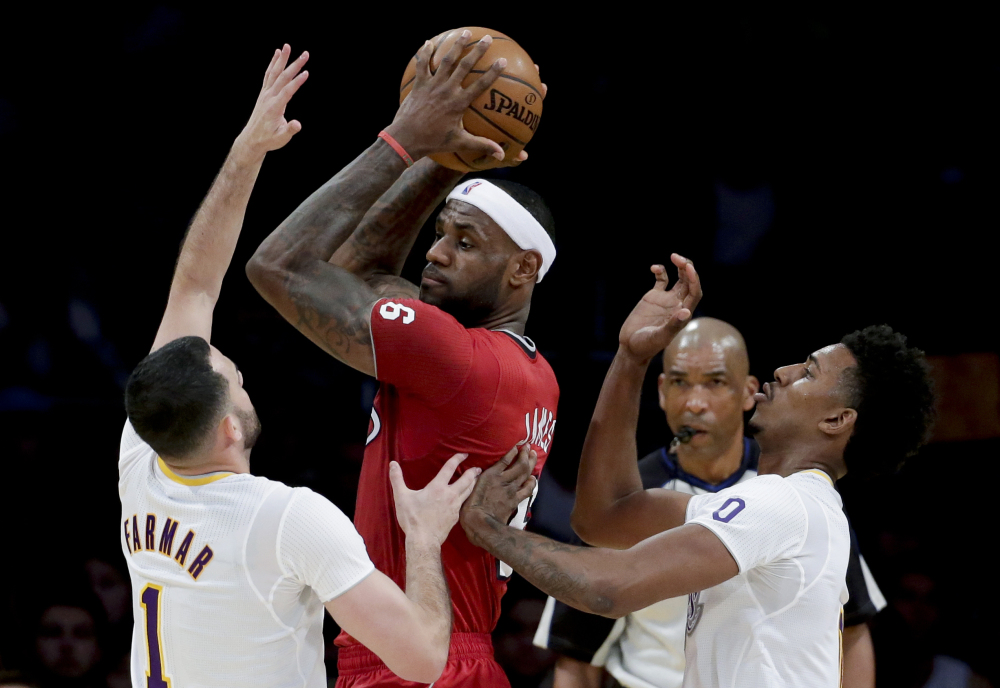 Miami Heat forward LeBron James, middle, is double-teamed by Los Angeles Lakers’ Jordan Farmar, left, and Nick Young during a game in Los Angeles on Wednesday.