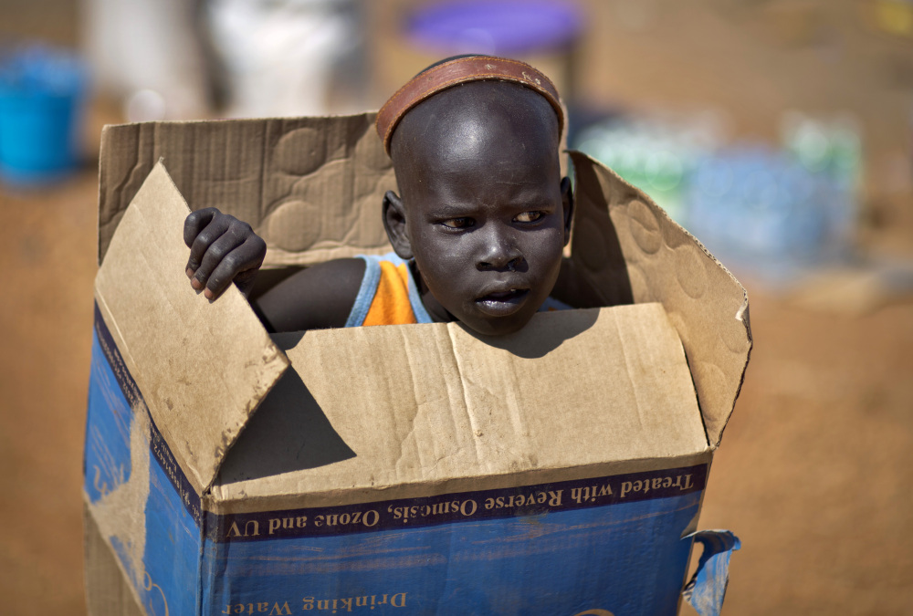 A displaced boy carries a cardboard box inside a United Nations compound which has become home to thousands of people displaced by the recent fighting, in Juba, South Sudan Friday, Dec. 27, 2013. Kenya’s president Uhuru Kenyatta on Friday urged South Sudan’s leaders to resolve their political differences peacefully and to stop the violence that has displaced more than 120,000 people in the world’s newest country, citing the example of the late Nelson Mandela and saying there is “a very small window of opportunity to secure peace” in the country where fighting since Dec. 15 has raised fears of full-blown civil war.