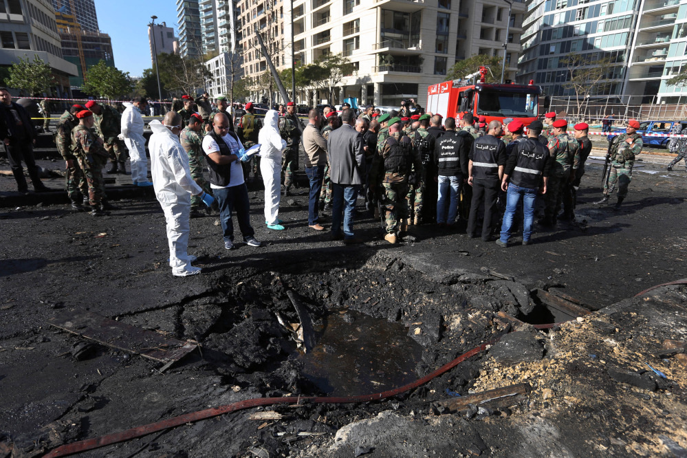 Lebanese army investigators in white coveralls stand next to a blast crater at the scene of an explosion in Beirut, Lebanon, Friday. A powerful car bomb tore through a business district in the center of the Lebanese capital Friday, killing Mohammed Chatah, a prominent pro-Western politician, and at least five other people.