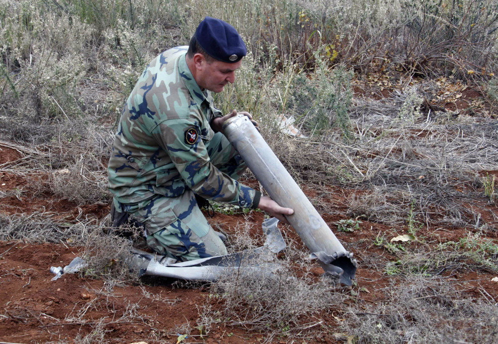 A Lebanese army soldier holds remains of a rocket that struck northern Israel, while inspecting an area in the southern village of Sarada, Lebanon, Sunday. Rockets from Lebanon struck northern Israel Sunday, causing no injuries but sparking an Israeli reprisal shelling in a rare flare-up between the two countries.
