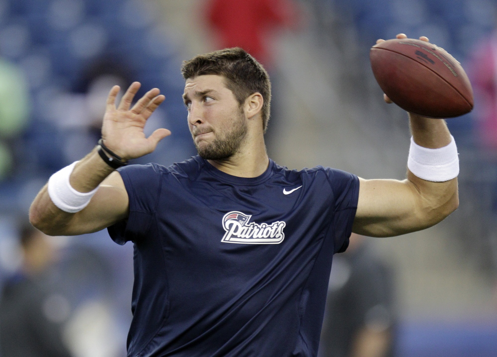 In this August 2013 file photo, former New England Patriots quarterback Tim Tebow warms up before an NFL preseason football game against the New York Giants. The Heisman Trophy winner has been hired as a college football analyst for the new SEC Network, but he still hopes to play quarterback in the NFL.