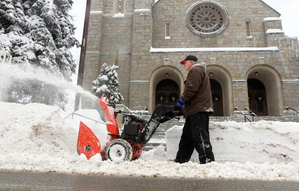 IN SERVICE OF THE CHURCH: Rich Garling of Waterville works to clear snow from Sunday night’s snow in front of Sacred Heart Catholic Church on Pleasant Street in Waterville on Monday. “This would be normal back in the day. Old Man Winter has returned,” said Garling, referring to all the snow that’s fallen this month.