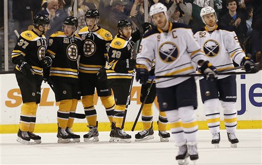 Boston Bruins' Reilly Smith, second from left, is congratulated by teammates Boston Bruins' Patrice Bergeron (37), Carl Soderberg and David Warsofsky (79) after scoring as Buffalo Sabres' Steve Ott (9) and Alexander Sulzer (52) skate away during the first period of Boston's 4-1 win in an NHL hockey game in Boston, Saturday, Dec. 21, 2013. (AP Photo/Winslow Townson)