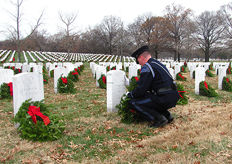 Portland Police Officer Kevin Haley pauses as he rests a wreath against the headstone of his brother, William Haley, at Arlington National Cemetery in Virginia. Kevin Haley is an advisory board member of Wreaths Across America, the Maine-based nonprofit that shipped 143,000 wreaths to Arlington. He is a coach of the Cheverus High School swim team, which sent more than a dozen members to Virginia for the wreath-laying ceremonies.