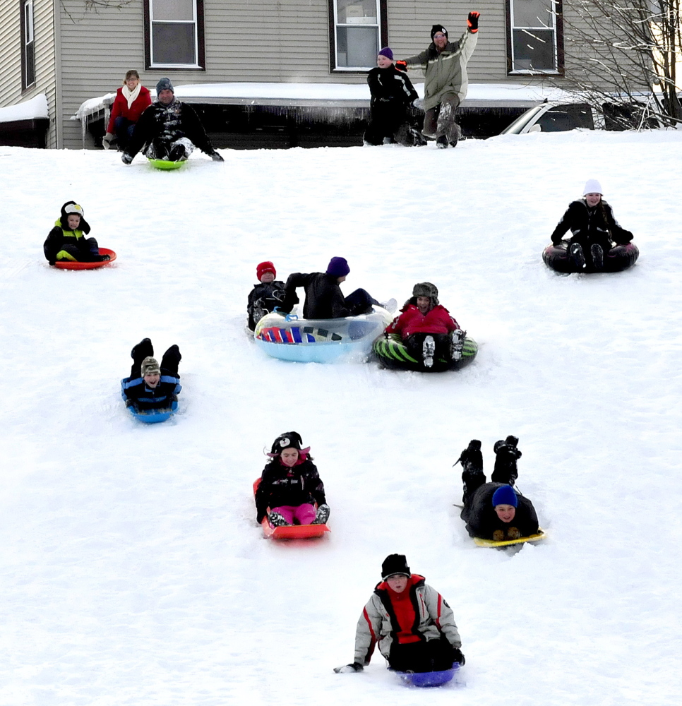 Staff photo by David Leaming WINTER FUN: Kids and adults race down the hill off Sherwin Street on sleds and tubes during the Inland Hospital sponsored Let's Go! Winter Fest in Waterville on Sunday, Jan. 5, 2014. People played outdoors sledding, snowshoeing and cross-country skiing.