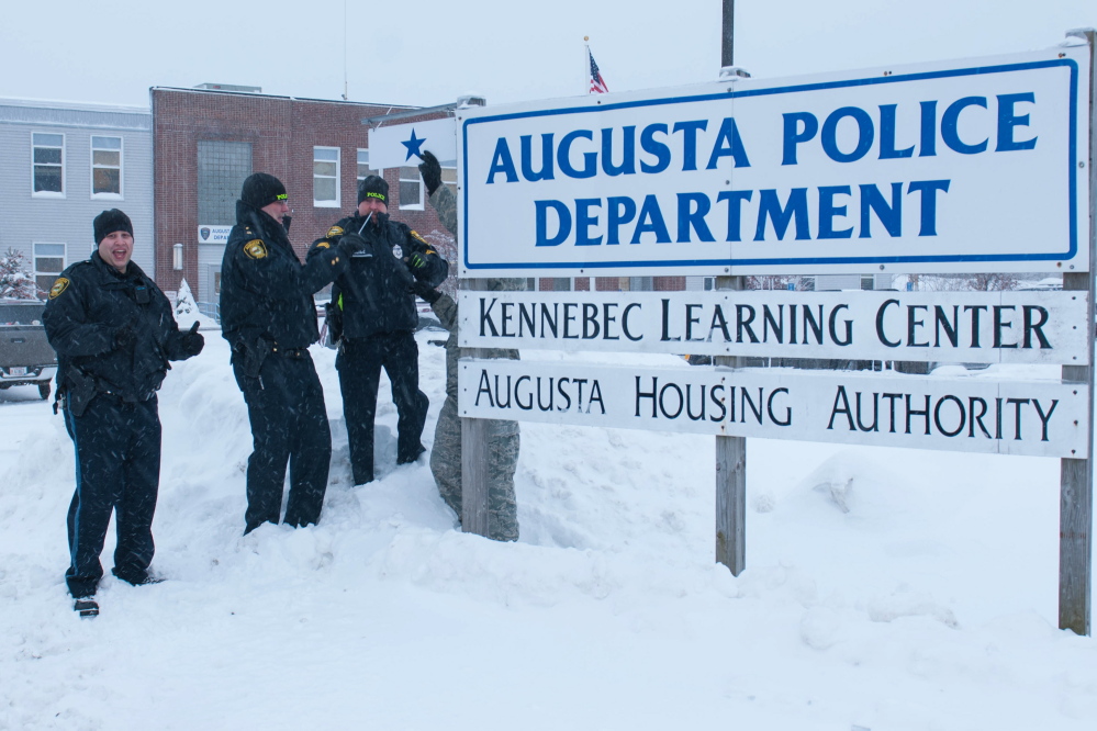 Augusta Police Department Chief Robert Gregoire, right, and Sgt. Christian Behr, center, hang a blue star beside the Augusta Police Department sign recently to honor patrolman and Air National Guard Staff Sgt. Brad Chase, left, who will deploy with the 101st Security Forces Squadron later this year. A brief ceremony was attended by Brig. Gen. Gerald Bolduc, commander of Maine Air National Guard, and Col. Eric Lind, director of staff, Maine Air National Guard. Behr and Gregoire each spoke to those in attendance. “He will be missed. He keeps things lively and always gets us laughing first thing in the day. He is an asset to this department,” Gregoire said at the ceremony. Chase joined the department in 2011. The star was hung as a sign of unity for the service member and his police department family.