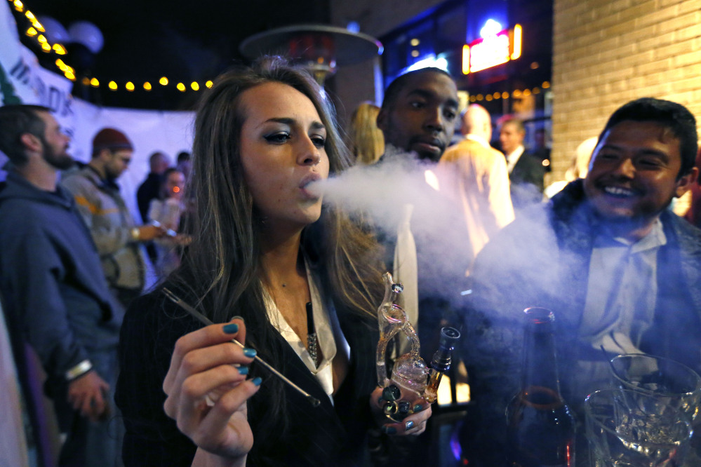 Partygoers smoke marijuana during a Prohibition-era themed New Year’s Eve party celebrating the start of retail pot sales, at a bar in Denver, late Tuesday.