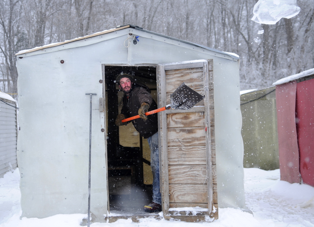 CLEANING OUT: Mike Abbott tosses ice out of a smelt shack Thursday at Baker’s Smelt Camps in Pittston. Abbott cleaned the ice out of race holes at the camps on the Kennebec River before anglers arrived to fish an afternoon tide.