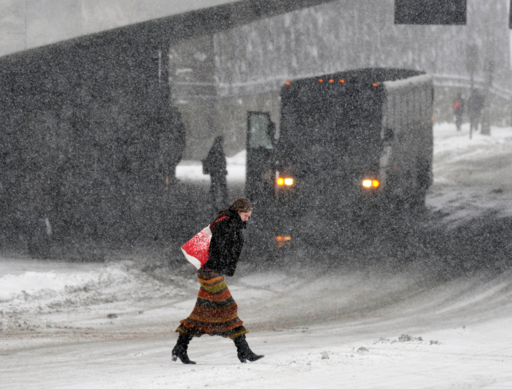 Marianne Stewart of Albany crosses a road as snow falls on Thursday in Albany, N.Y. The National Weather Service said some areas from Buffalo to Albany could get a total of up to 14 inches by the time the coastal storm moved out Friday morning.
