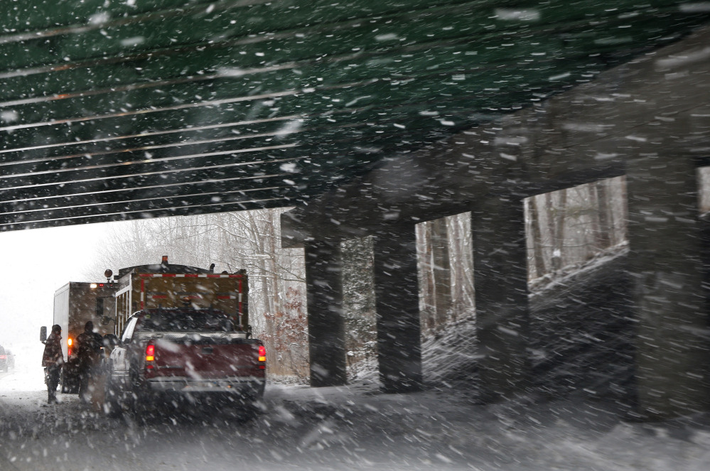 A salt and sand road crew regroups under a bridge as snow falls in Andover, Mass., on Thursday. Up to 14 inches of snow is forecast for the Boston area.