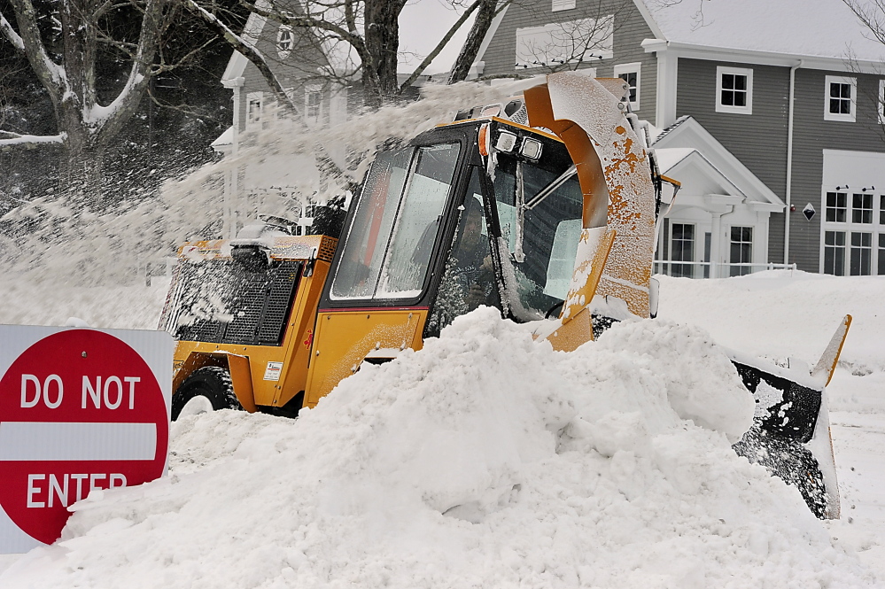 Eric Gibson, an employee of Freeport Public Works, grinds through some pretty deep snow drifts Friday as he cleans the sidewalk in Freeport near Bath Savings Bank. Gordon Chibroski, Staff Photographer
