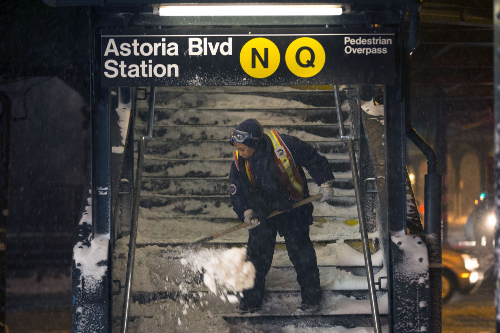 A worker clears snow from a stairway at the Astoria Blvd. subway station Friday in the Queens borough of New York. New York City public schools were closed Friday after up to 7 inches of snow fell by morning.