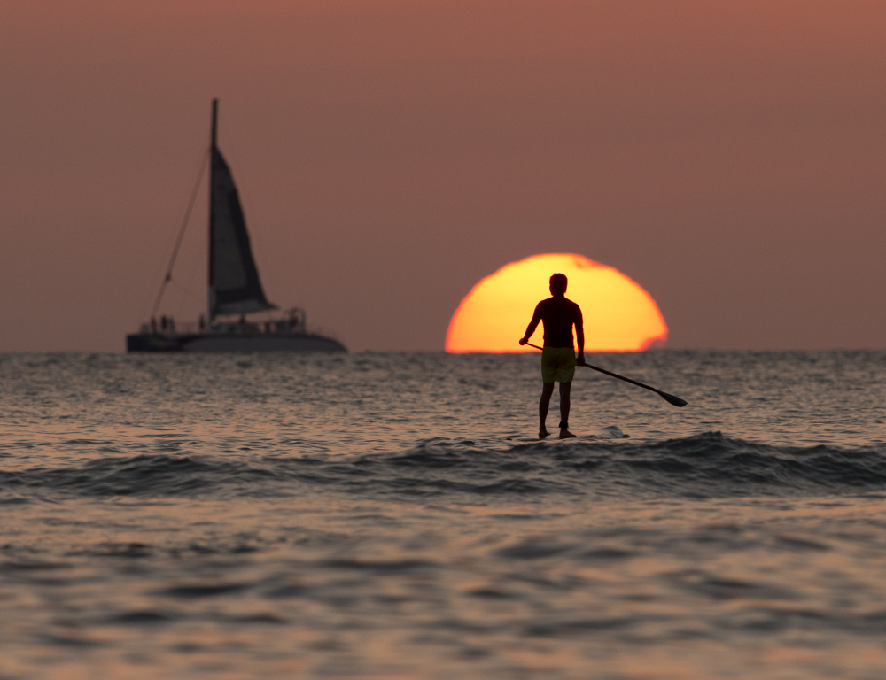 A paddle boarder plies waters off Waikiki Beach. Hawaii has acted progressively on the environment, a stance that puts off new business, one of its rare Republican leaders says.