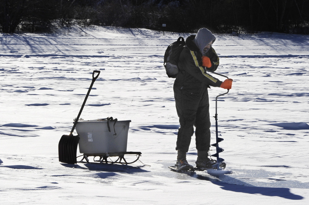 Walter Selens of Gorham uses a hand auger Saturday to cut a hole for fishing on Sebago Lake’s Lower Bay in Standish.