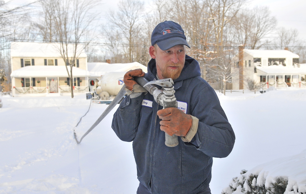 Staff photo by Michael G. Seamans WINTER HEAT: Greg French, a 15-year veteran delivery man for Dead River Oil, trudges through deep snow to make a delivery on Primrose Street in Winslow on Friday. French said it has been busier than usual compared to previous years. “We haven’t seen cold like this in a long time. Usually there is a bit of relief with a thaw. Not this year,” French said.