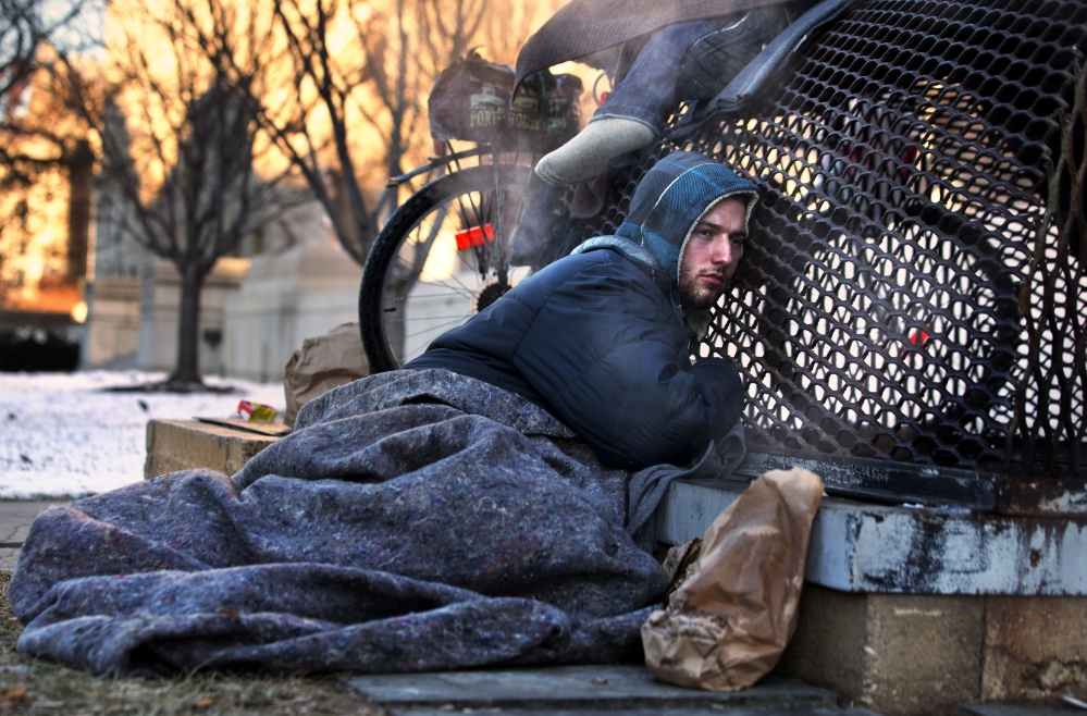 Nicholas Simmons, 20, of Greece, N.Y., warms himself on a steam grate with three homeless men by the Federal Trade Commission, just blocks from the Capitol, during frigid temperatures in Washington, on Saturday.