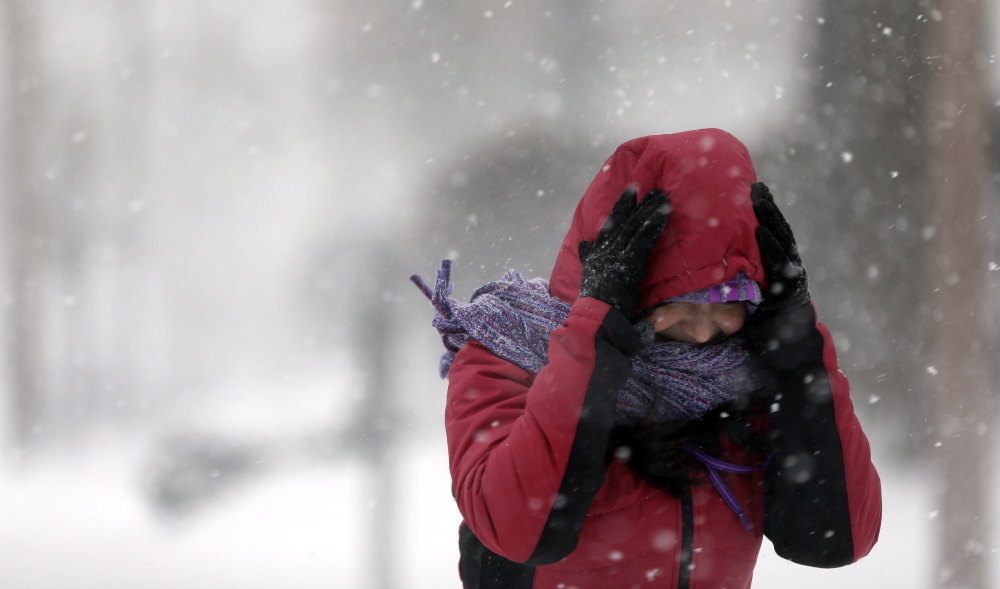 Srirupa Chatterjee holds her hood as she crosses a street in St. Louis on Sunday. Heavy snow continued to fall Sunday, with forecasters calling for up to a foot in eastern Missouri and parts of central Illinois followed by bitter cold.