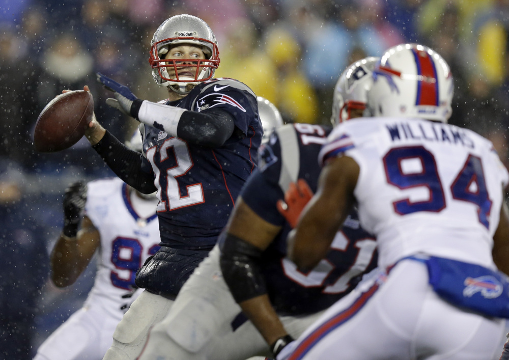 New England Patriots quarterback Tom Brady (12) passes against Buffalo Bills defensive end Mario Williams (94) in the first quarter of an NFL football game, Sunday, Dec. 29, 2013, in Foxborough, Mass. (AP Photo/Steven Senne)
