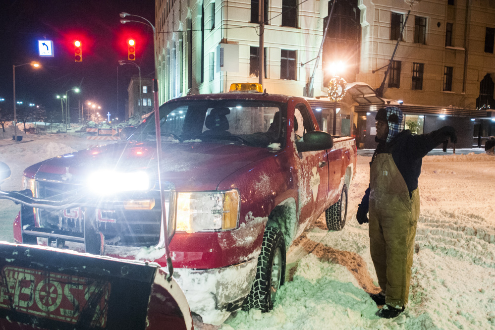 Leroy Griffis, a maintenance supervisor for the Flint Downtown Development Authority directs a snowplow to an assignment where he will clear streets early Monday in downtown Flint, Mich., where a recorded 16.2 inches of snow fell.