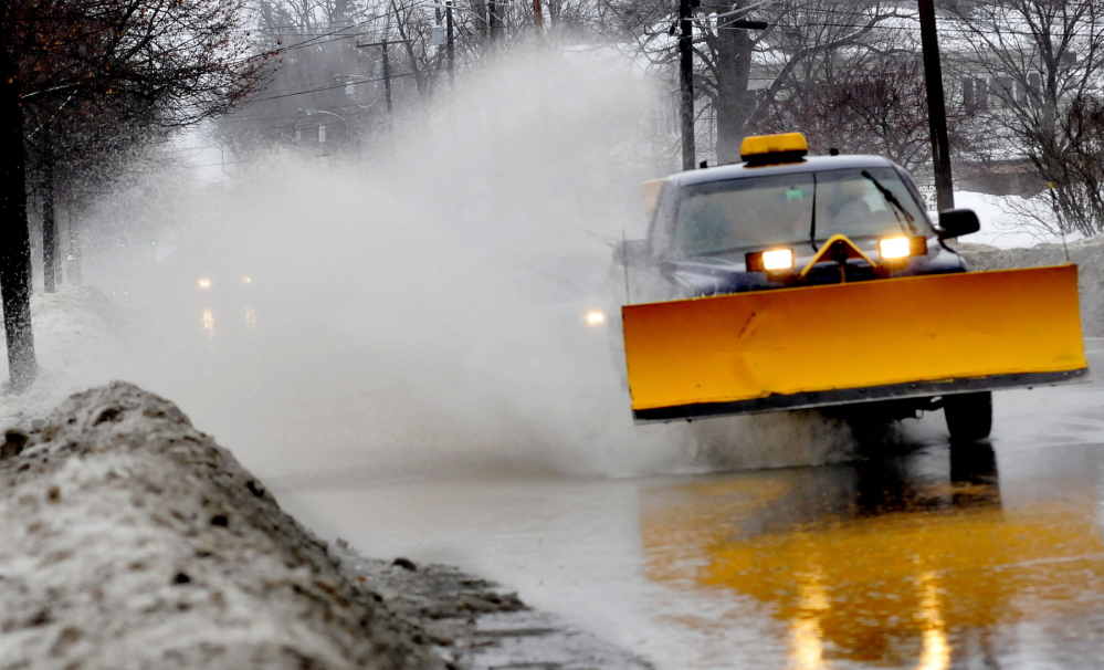 BLAST OFF: A plow truck drives through a flooded street in Waterville sending a rooster tail of spray in its wake on Monday.