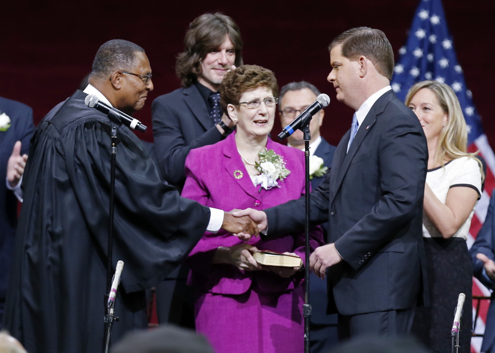 Boston Mayor Marty Walsh, right, shakes hands with Massachusetts Supreme Court Chief Justice Roderick Ireland after taking the oath of office in Conte Forum at Boston College on Monday.