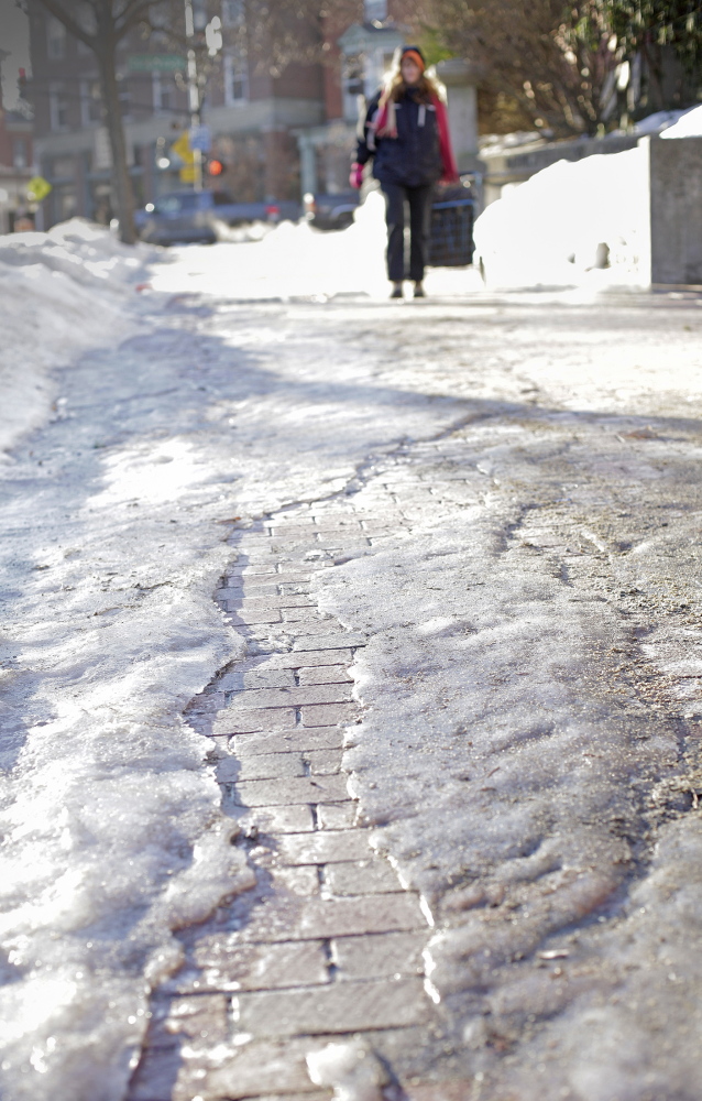 Morning temperatures around 14 degrees freeze the ice on sidewalks along State Street, making walking difficult in Portland on Tuesday.